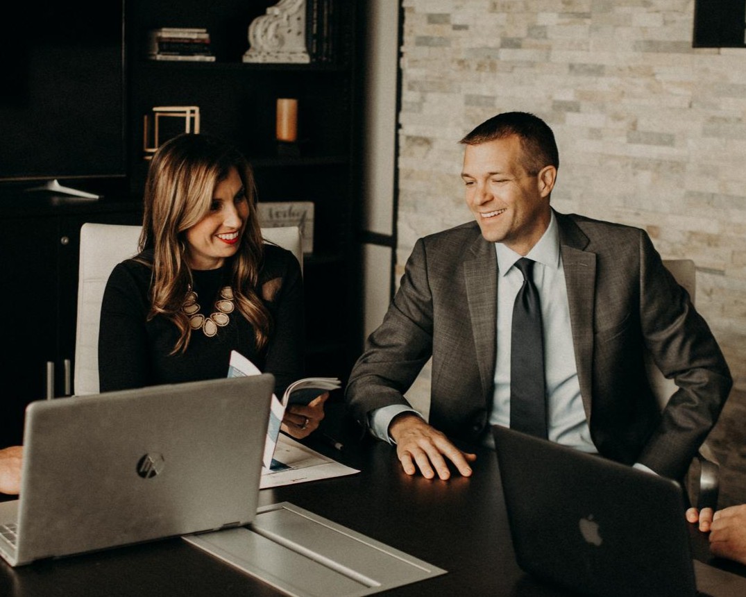 Three colleagues sitting together at a table, focused on their laptops in a professional setting.